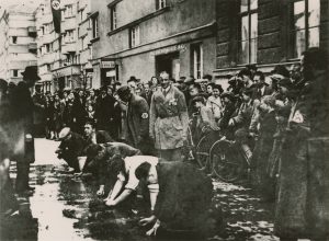 Po aneksji Austrii przez Trzecią Rzeszę mieszkańcy stolicy przyglądają się, jak austriaccy naziści zmuszają Żydów do szorowania chodnika. Wiedeń, marzec 1938 r. Dokumentationsarchiv des österreichischen Widerstandes